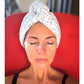 Woman with a towel wrapped around her head sitting on a red chair.